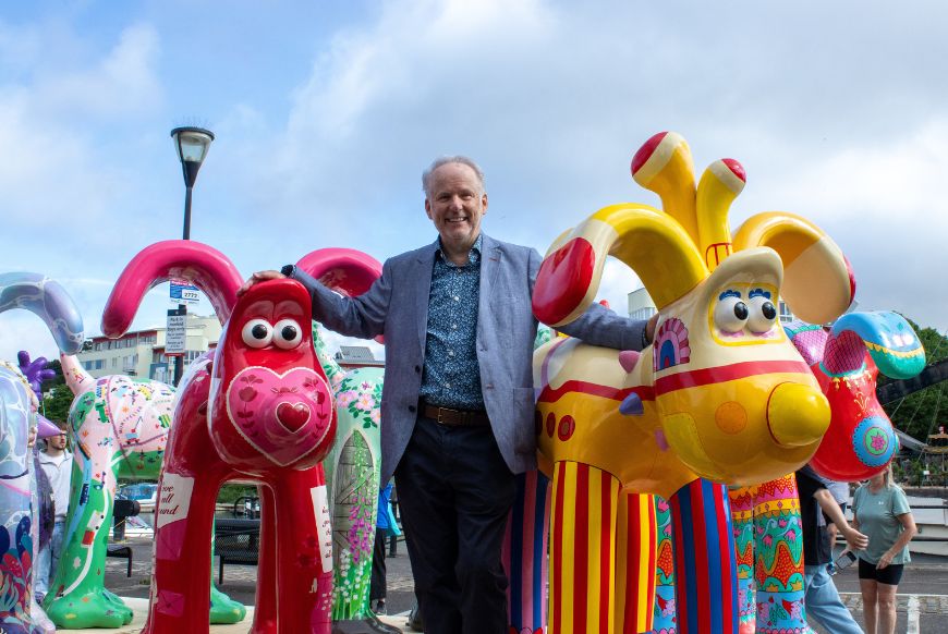 Nick park next to statues of gromit